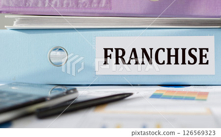 FRANCHISE. Word written on folder with documents and calculator. 126569323