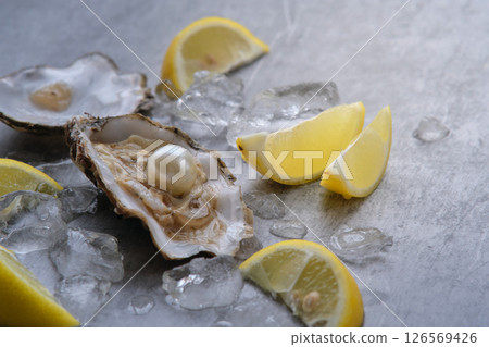 Oyster with pearl and lemons on a gray background Oyster with pearl and lemons on a gray background 126569426
