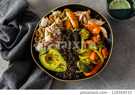 Nutritious, wholesome breakfast featuring quinoa, avocado, roast chicken, and roasted vegetables like sweet potato, zucchini, and broccoli, complemented with a fresh cabbage and radish salad 126569533