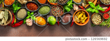 A rich palette of colorful spices and herbs, resting on a brown background, radiating freshness and an inviting aroma, perfect for gourmet inspiration, banner 126569692