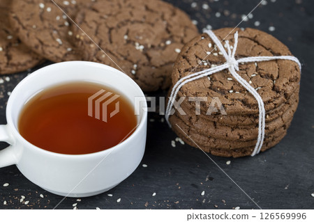 chocolate biscuits with real cocoa and sesame, a cup of tea next to a cookie chocolate biscuits with real cocoa and sesame, a cup of tea next to a cookie 126569996