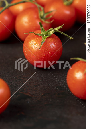 wet small red tomatoes during cooking, cherry tomatoes on the table with small green tails, close up wet small red tomatoes during cooking, cherry tomatoes on the table with small green tails, close up 126570002