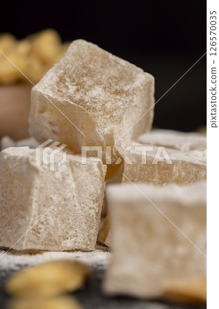 Turkish delight in with nuts , scattered oriental sweets Turkish delight with peanuts on a black board, closeup, side view Turkish delight in with nuts , scattered oriental sweets Turkish delight with peanuts on a black board, closeup, side view 126570035