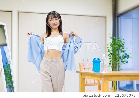A young woman in casual clothes takes off her clothes, gets changed and heads to the gym Yoga Stretching Diet Health 126570073