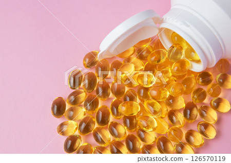 Vitaminen Omega 3 oil in capsules on pink background. Much medical pills and drugs in white plastic bottle. Healthcare concept. Vitaminen Omega 3 oil in capsules on pink background. Much medical pills and drugs in white plastic bottle. Healthcare concept. 126570119