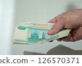Hand holding a bunch of 1000-ruble bills. Symbol of salary, expenses, income. 126570371