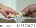 Female and male hands holding or handing over a bundle of euros. Financial transaction. 126570374