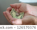 Cupped male hands holding a $20 bill and a quarter 126570376