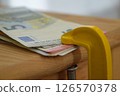 Euro banknotes are clamped in a metal vise 126570378