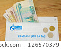 Several bills (Russian rubles) stick out of the gas bill for the apartment, there are some coins on top 126570379