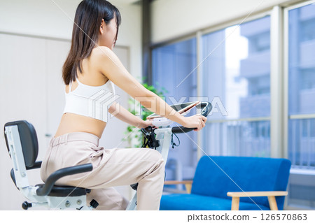 Woman exercising on a fitness bike in her home room, home, exercise bike, exercise 126570863