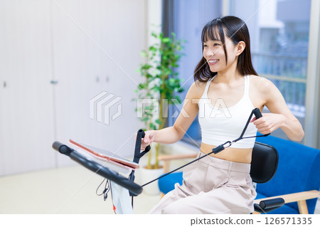 Woman exercising on a fitness bike in her home room, home, exercise bike, exercise 126571335