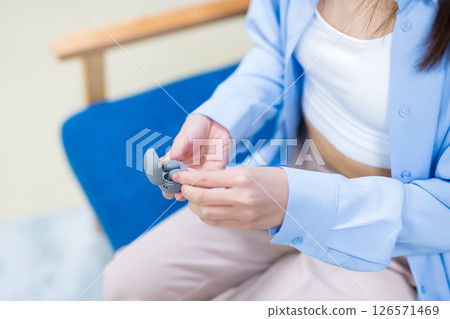 A woman's hand holding a commercially available wireless earphone 126571469