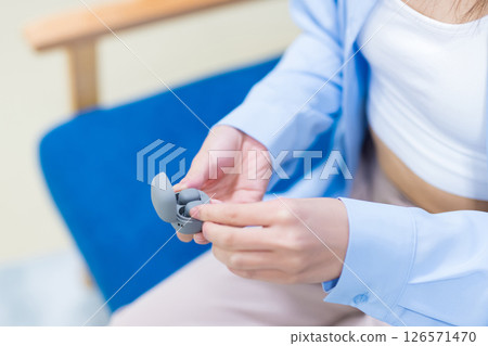 Cropped photo of a woman's hand picking up a commercially available wireless earphone 126571470