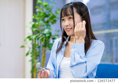 A woman picking up commercially available wireless earphones 126571477
