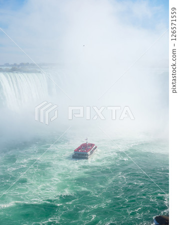 Niagara Falls. A pleasure boat with people near the huge famous waterfall. Niagara Falls. A pleasure boat with people near the huge famous waterfall. 126571559