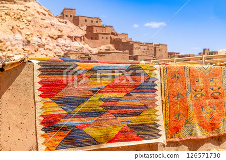 Colorful traditional carpets gifts selling on the market streets of ancient Ait Benhaddou ksar village, Ouarzazate province, Morocco 126571730