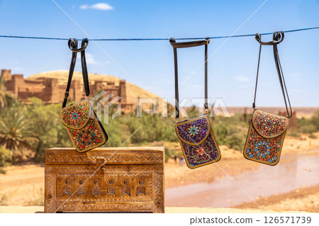 Colorful traditional souvenir bags wallets selling on the market streets of ancient Ait Benhaddou ksar village, Ouarzazate province, Morocco 126571739