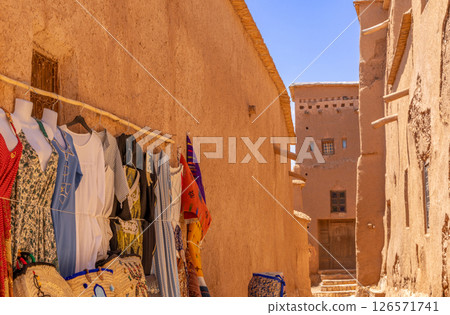 Colorful traditional dresses selling on the market streets of ancient Ait Benhaddou ksar village, Ouarzazate province, Morocco 126571741