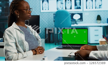 Doctor and patient discuss about health care recovery next to mockup screen, meeting in cabinet to share advice and medicine. Professional medic consulting girl during routine checkup. Camera A. Doctor and patient discuss about health care recovery next to mockup screen, meeting in cabinet to share advice and medicine. Professional medic consulting girl during routine checkup. Camera A. 126572389