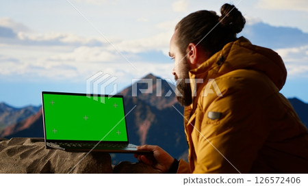 Thrilled traveler enjoying the panoramic beauty with a green screen device, looking out at the rugged mountain range. Endless landscape symbolize personal growth, freedom. Camera B. Thrilled traveler enjoying the panoramic beauty with a green screen device, looking out at the rugged mountain range. Endless landscape symbolize personal growth, freedom. Camera B. 126572406