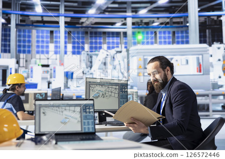 Inspector in photovoltaics factory investigating against malfunctioning systems, reading paperwork. Supervisor inspecting solar panels manufacturing plant to reducing downtime, checking documents 126572446