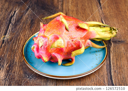 Whole and ripe unpeeled pitahaya on a plate. Whole and ripe unpeeled pitahaya on a plate. 126572510
