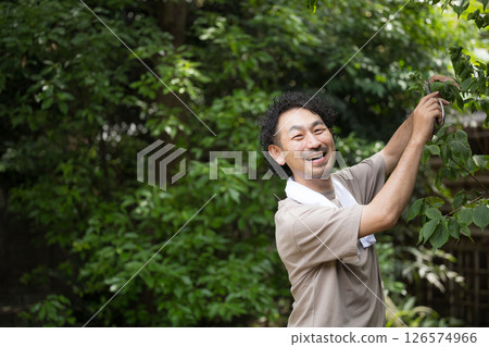 Image of a gardener pruning, looking at the camera 126574966