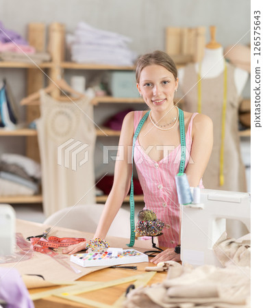 Young woman seamstress posing in sewing workshop Young woman seamstress posing in sewing workshop 126575643
