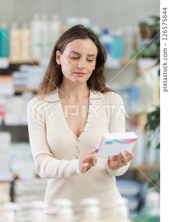 Adult woman chooses pills at pharmacy Adult woman chooses pills at pharmacy 126575644