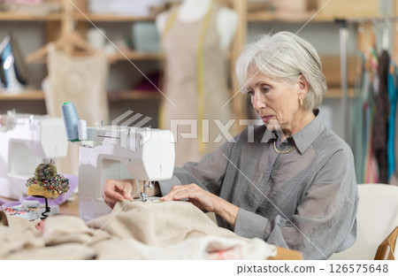 Woman seamstress sews on sewing machine in workshop 126575648