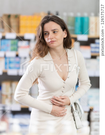 Adult woman with stomach pain at pharmacy Adult woman with stomach pain at pharmacy 126575717