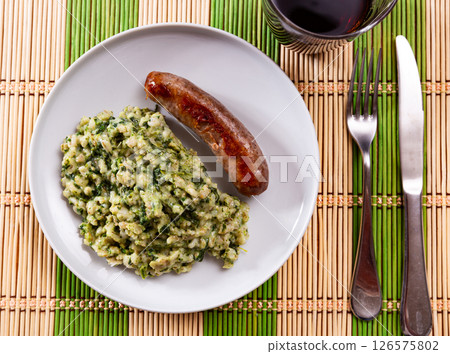 Fatty fried homemade pork weenie sausage with side dish of pearl barley with spinach. Fatty fried homemade pork weenie sausage with side dish of pearl barley with spinach. 126575802