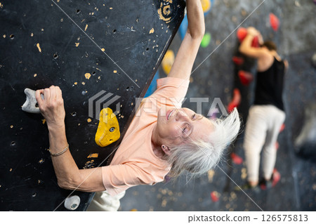 elderly active female pensioner reached top of bouldering wall elderly active female pensioner reached top of bouldering wall 126575813