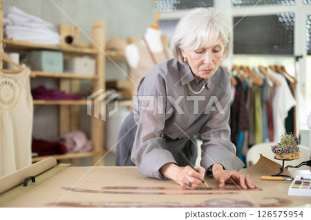 Mature fashion designer drawing on paper Mature fashion designer drawing on paper 126575954