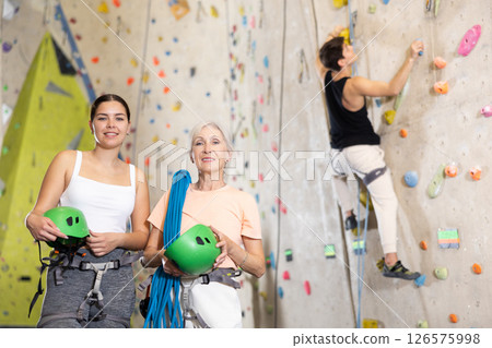 two active female marathon participants are standing in climbing hall 126575998