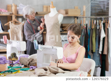 Young woman sews on machine female assistant sews on mannequin 126576029