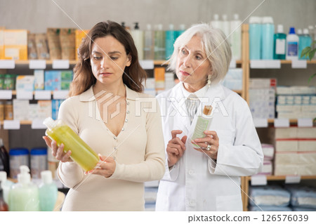 woman chooses shampoo in a pharmacy against the background of a pharmacist 126576039