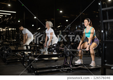 During training session in mini group of athletes, woman exercises on cable crossover machine During training session in mini group of athletes, woman exercises on cable crossover machine 126576046