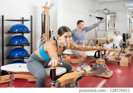 Young woman stretching her arms using pilates machine 126576051