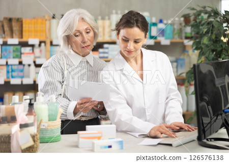 Woman pharmacist at computer communicate with senior female client Woman pharmacist at computer communicate with senior female client 126576138