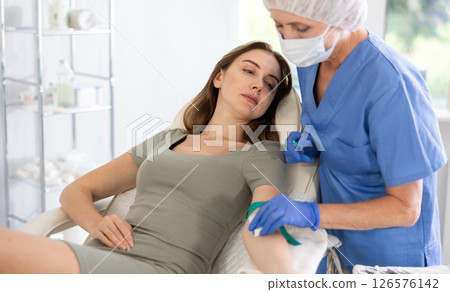 Elderly doctor drawing blood from young patient. Elderly doctor drawing blood from young patient. 126576142