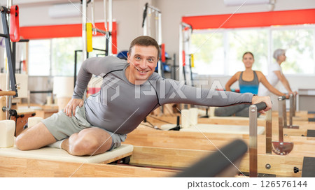 Man performs exercise on reformer to improve coordination, balance, and posture 126576144