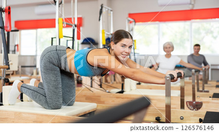 Girl performs exercise on reformer to improve coordination, balance, and posture 126576146