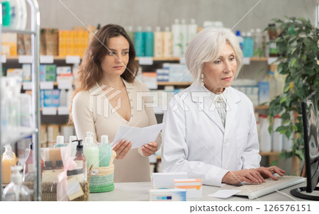 Senior woman pharmacist at computer communicate with female client 126576151
