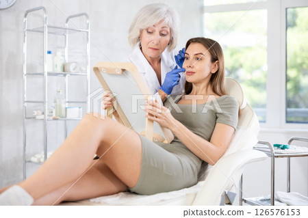 Cosmetologist with gloves preparing patient to skin care procedure in spa salon. Cosmetologist with gloves preparing patient to skin care procedure in spa salon. 126576153