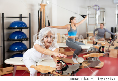 Mature woman during Pilates training performs exercises and tasks on heron pulley tower Mature woman during Pilates training performs exercises and tasks on heron pulley tower 126576154
