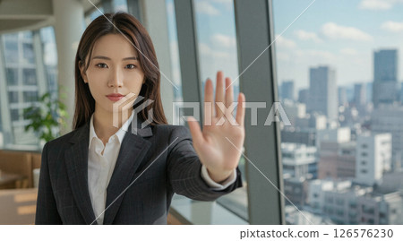 A woman in a suit making a stop gesture indoors A woman in a suit making a stop gesture indoors 126576230