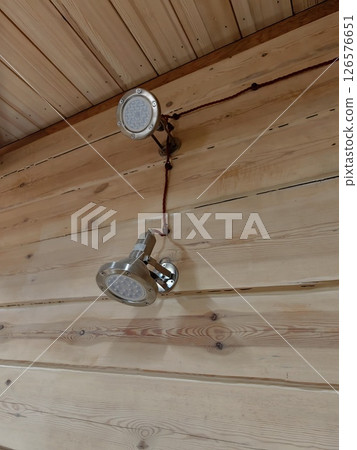 modern ceiling lights installed on natural wood paneling in cozy indoor setting. closeup. modern ceiling lights installed on natural wood paneling in cozy indoor setting. closeup. 126576651