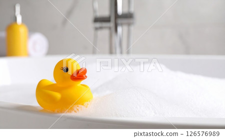 A fun yellow plastic rubber duck toy floats in the baby's bathwater A fun yellow plastic rubber duck toy floats in the baby's bathwater 126576989